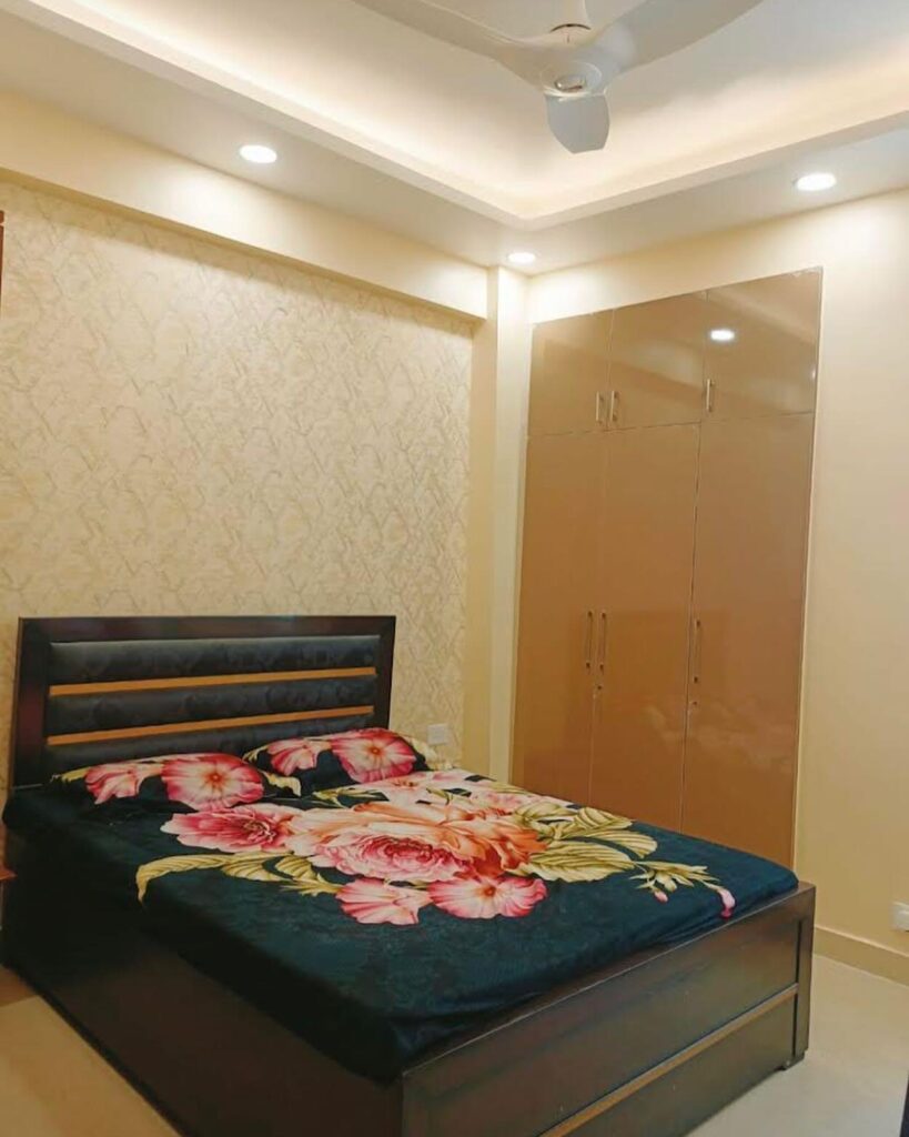 Discover exquisite interior design services in Noida, featuring a stunning high gloss laminate finish on the master bedroom's beautiful wooden wardrobe.