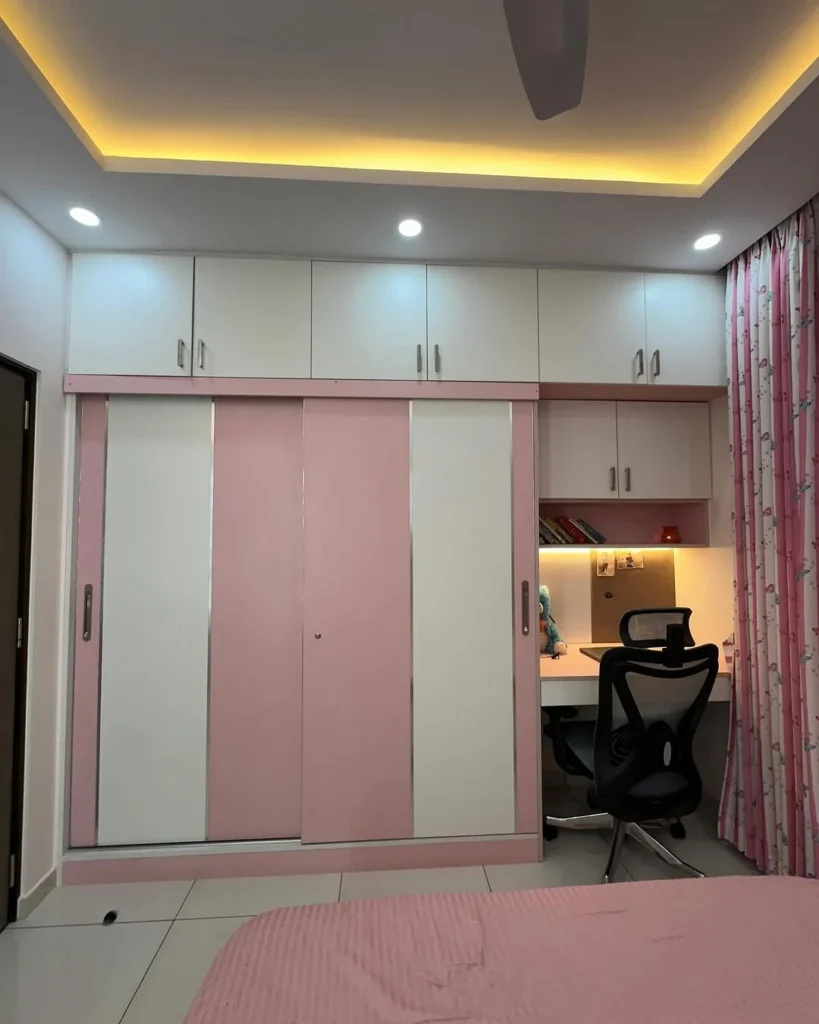Charming Pink and White Sliding Wardrobe with Top Storage Cabinet
This stylish wardrobe design offers a delightful blend of color and functionality. The soft pink and white tones create a calm and inviting atmosphere, while the sleek sliding doors ensure space-saving and convenience. The wardrobe also includes an upper storage cabinet, making it an excellent solution for organizing a bedroom while adding a cheerful aesthetic to the room. The simple, minimalistic design with clean lines and smooth finishes elevates the room's look, making it perfect for modern interiors.
Wardrobe Design Details:
Type: Sliding Door Wardrobe with Upper Storage Cabinet
Doors: 2 Sliding Doors with Soft Pink and White Panels
Wardrobe Dimensions (WxDxH): Approx. 6 x 2 x 8 feet
Style: Modern Minimalistic
Colour: Soft Pink (Panels), White (Main Doors and Cabinet)
Wardrobe Shutters: Smooth laminate finish
Special Features: Upper storage cabinet, sleek sliding door mechanism, minimalistic design
Design Benefits:
The soft pink and white color scheme adds a calm and warm touch to any bedroom.
Sliding doors maximize space, offering easy access to wardrobe contents without needing extra room.
The upper storage cabinet provides additional space for organizing books, decor, or other items.
The clean and simple design integrates well with a variety of room styles.
Ideal for bedrooms where storage and aesthetics need to be balanced seamlessly.
