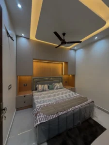 A Space-Saving Bedroom Design with Overhead Storage and Warm Headboard Panel