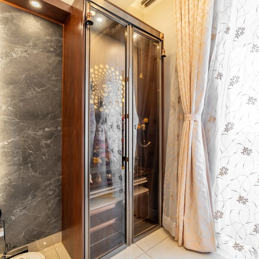 A Compact Mandir Design with Glass Doors and Marble Back Panel